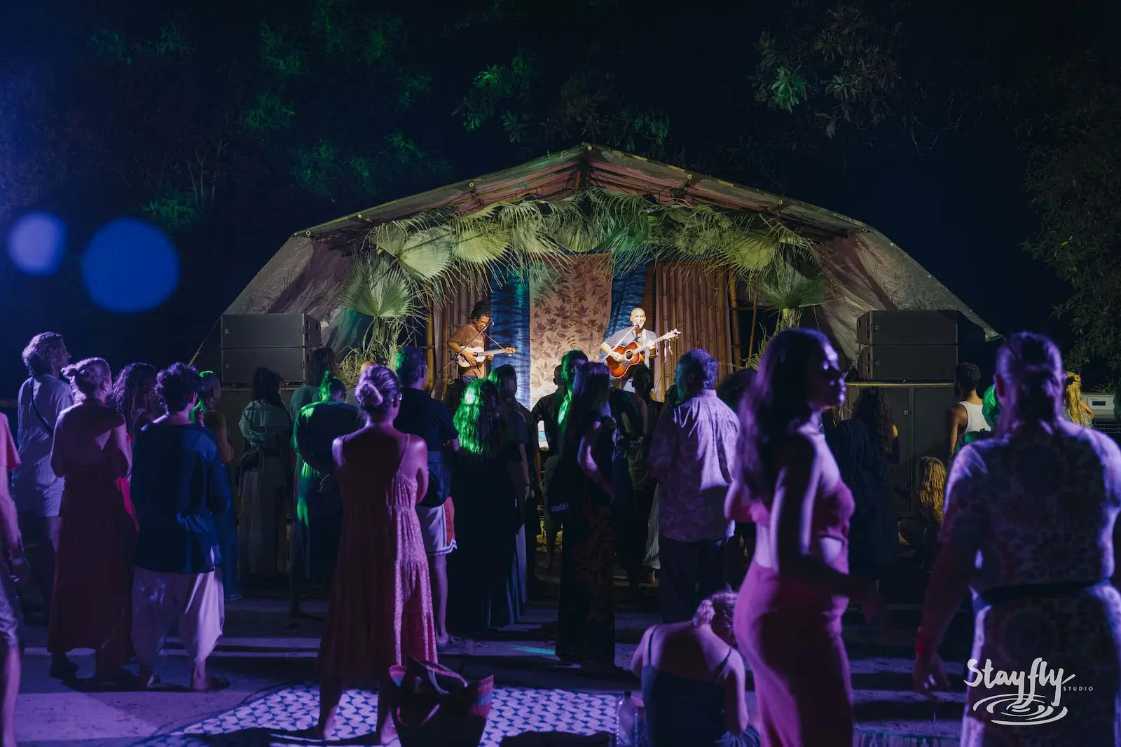 Crowd gathered before a lit stage at night.