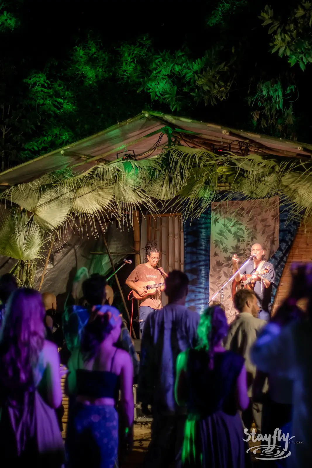 Crowd before a thatched night stage with musicians.