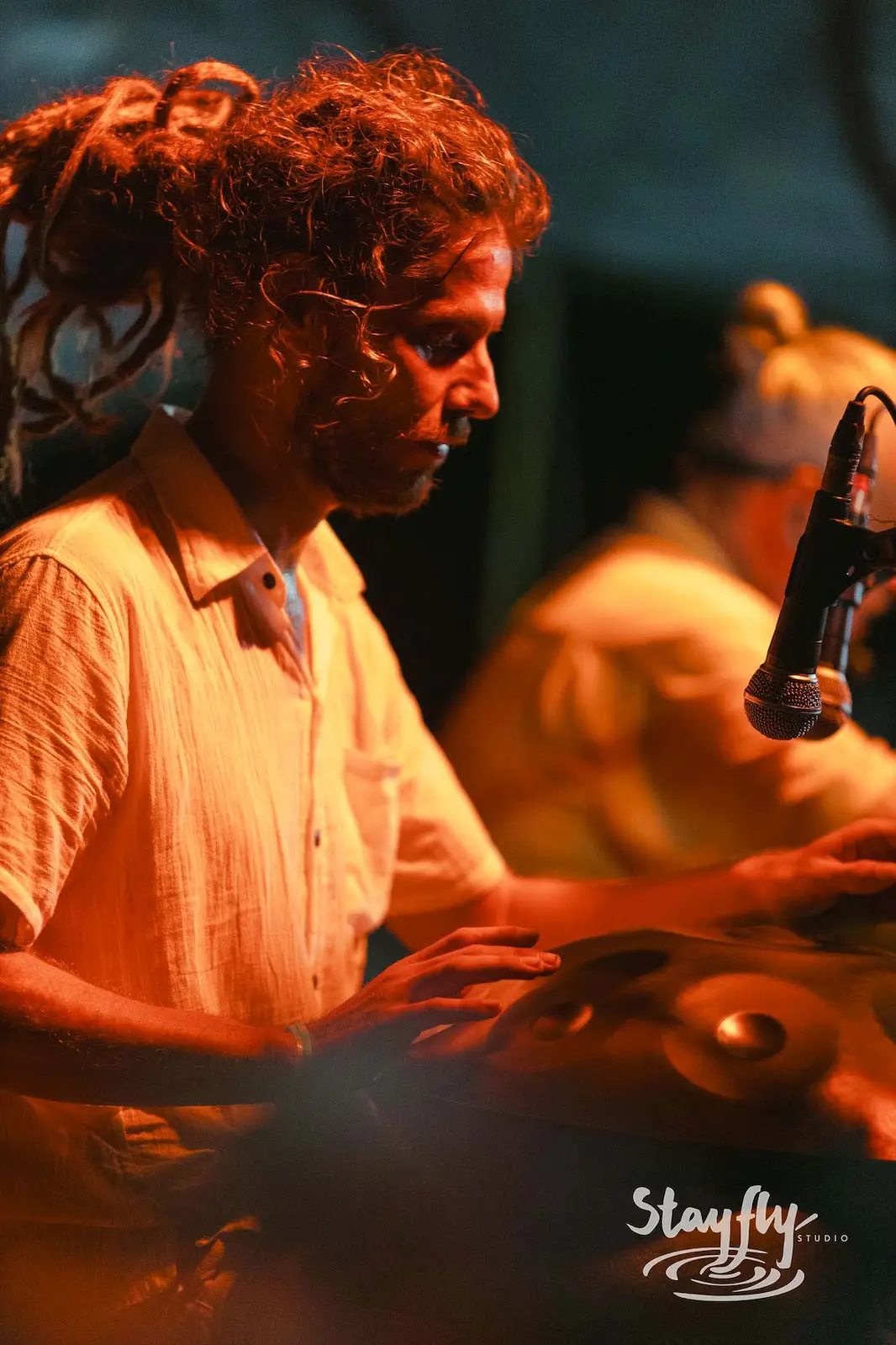 Man playing a handpan drum at night.