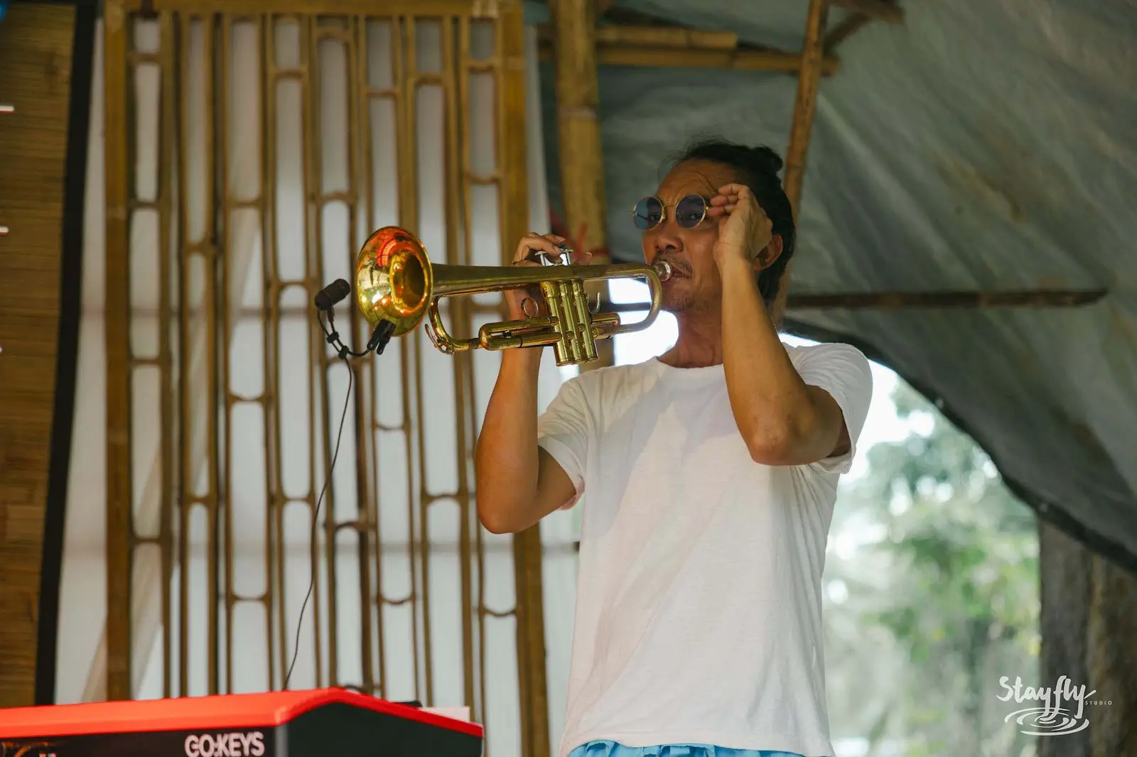 Trumpet player performing on bamboo stage.
