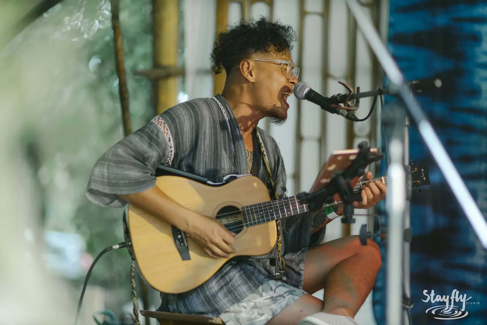 Guitarist singing into microphone outdoors.
