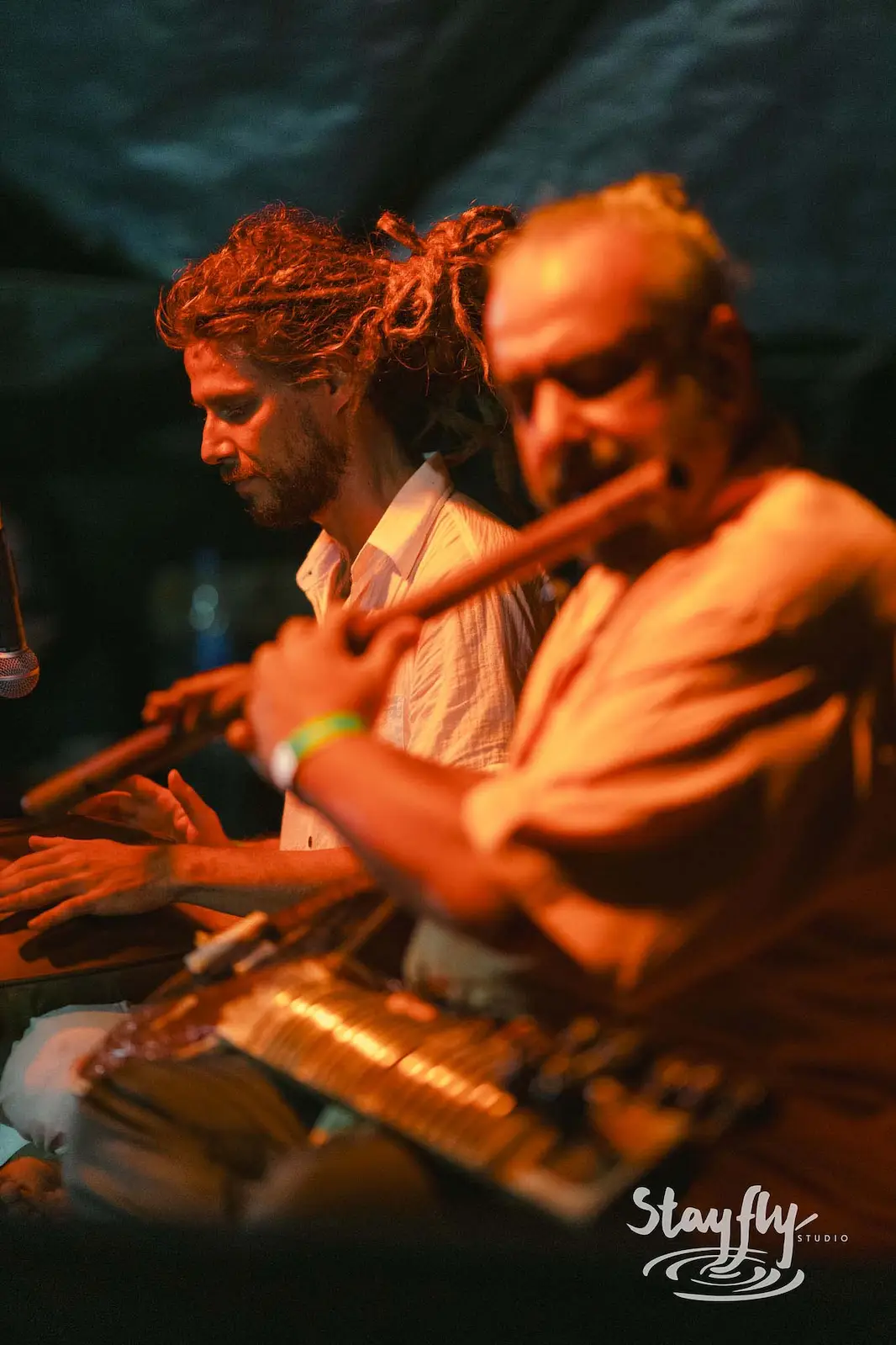 Two musicians playing flute and hand drums.