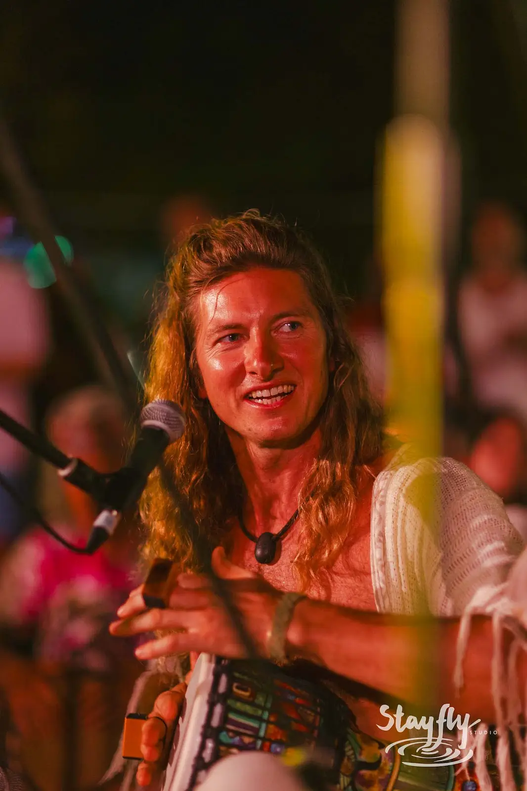 Drummer smiling while playing hand drum.