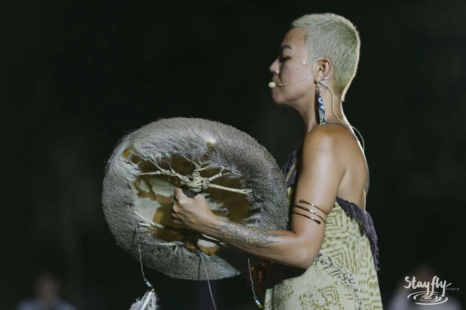 Performer playing frame drum on stage.