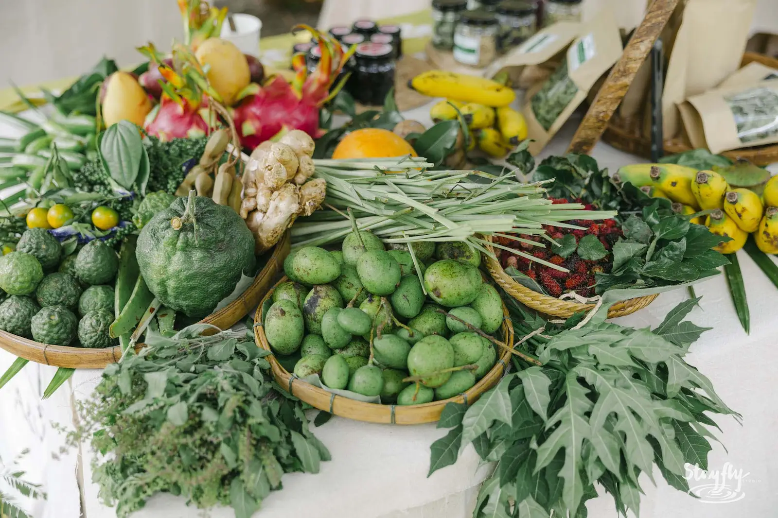 Market table of fresh produce, jars and greens.