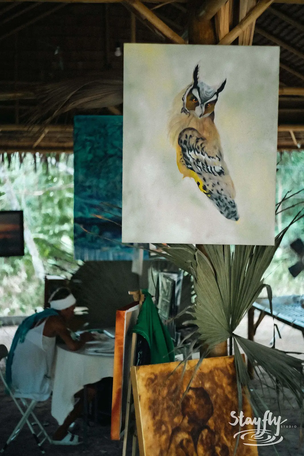Owl painting displayed at outdoor art stall.
