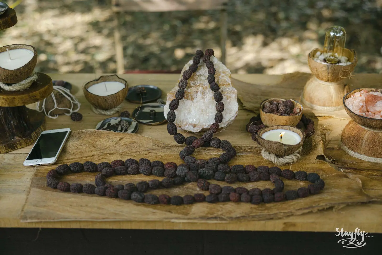 Mala beads and crystal displayed on wood table.