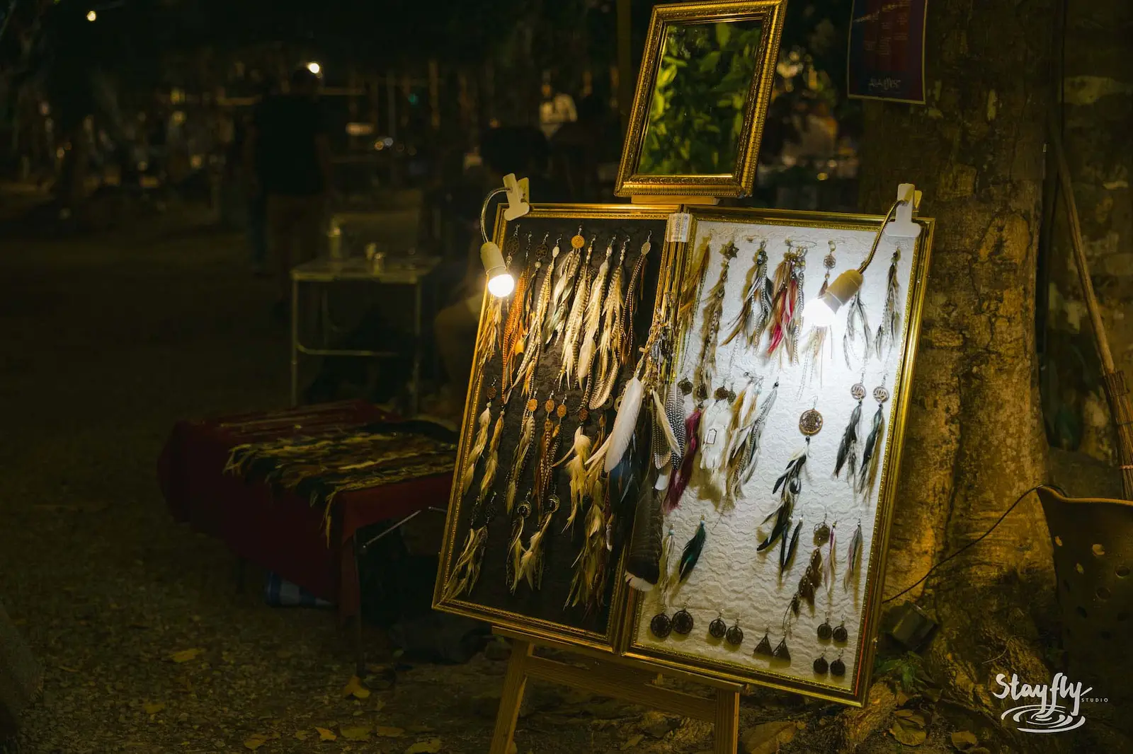 Framed fishing flies displayed at night market stall.
