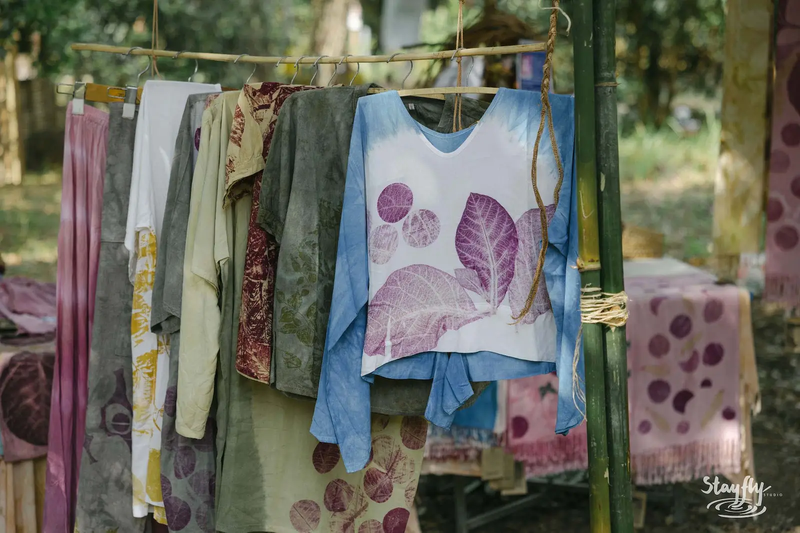 Eco-printed clothing hanging on market rack.
