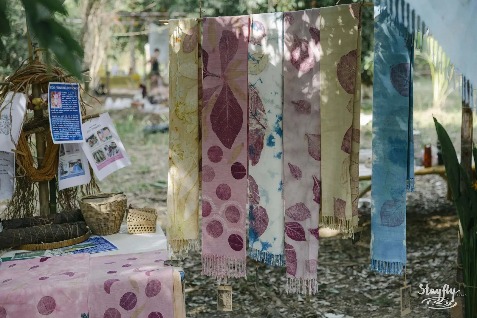 Eco-printed scarves hanging at market stall.