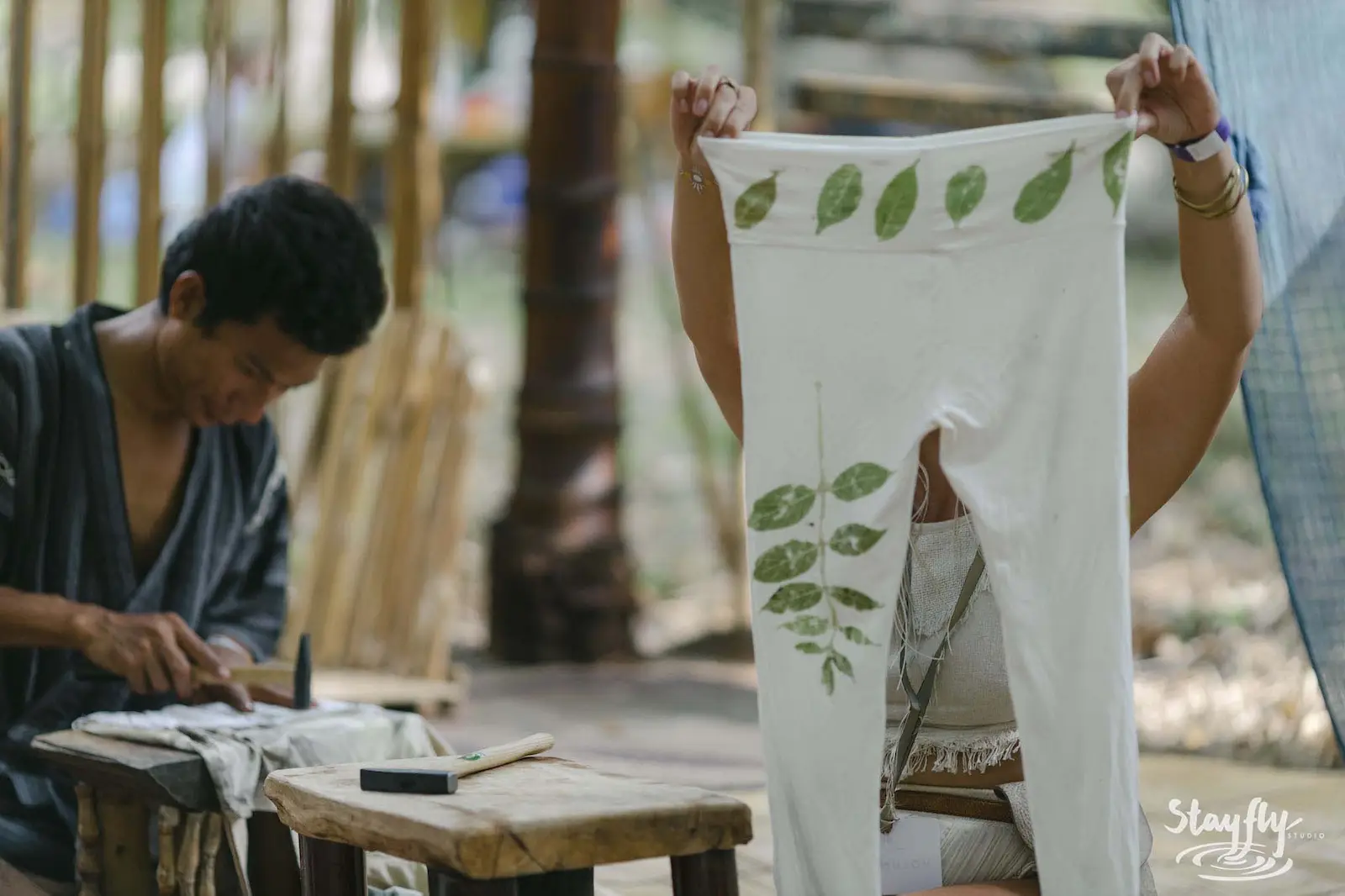Person holding up eco-printed leaf-pattern garment.
