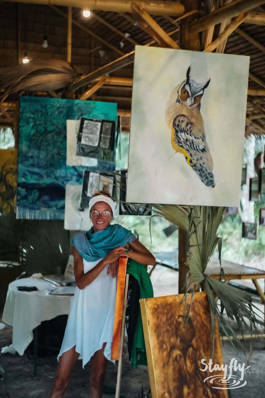 Artist standing beside bird painting exhibit.