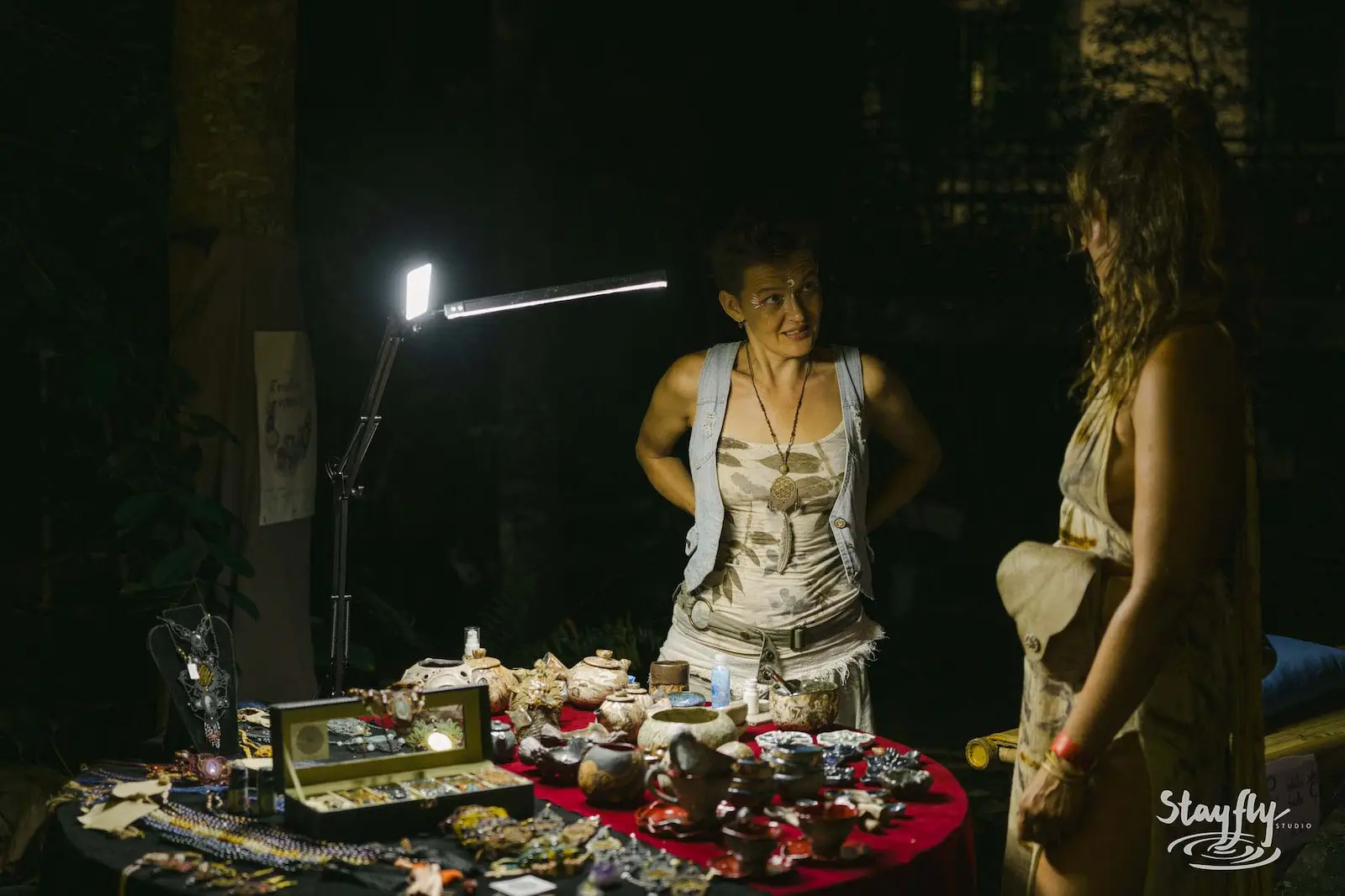 Vendor showing jewelry to customer at night market.