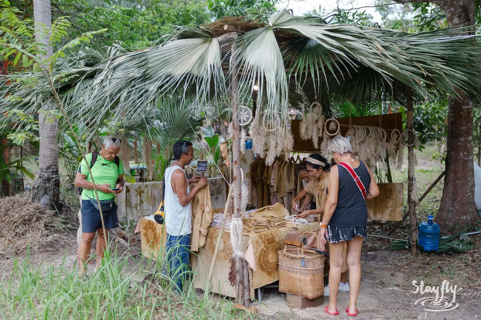 Shoppers browsing bamboo craft stall with dreamcatchers.
