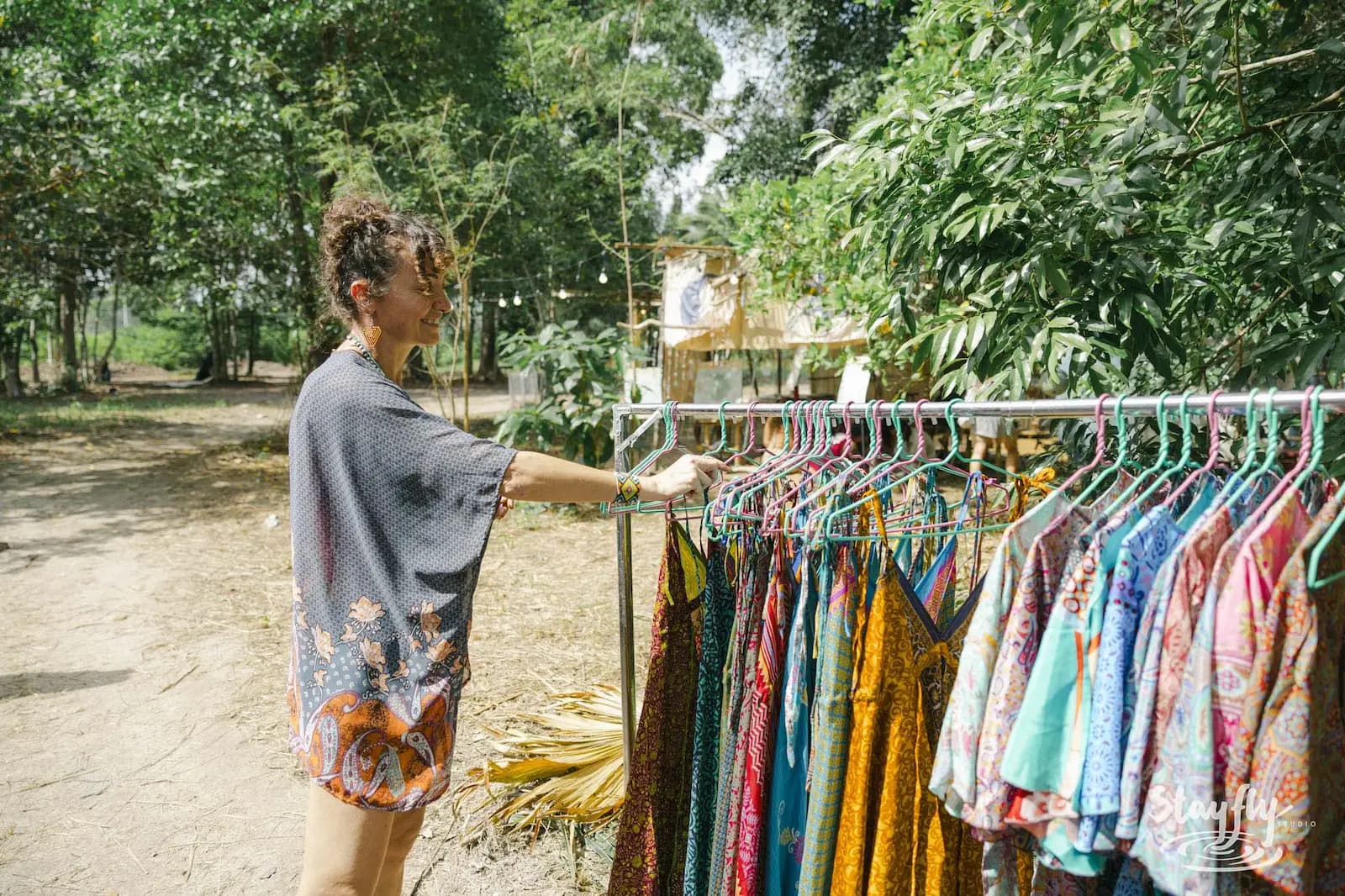 Woman browsing clothing rack at market.