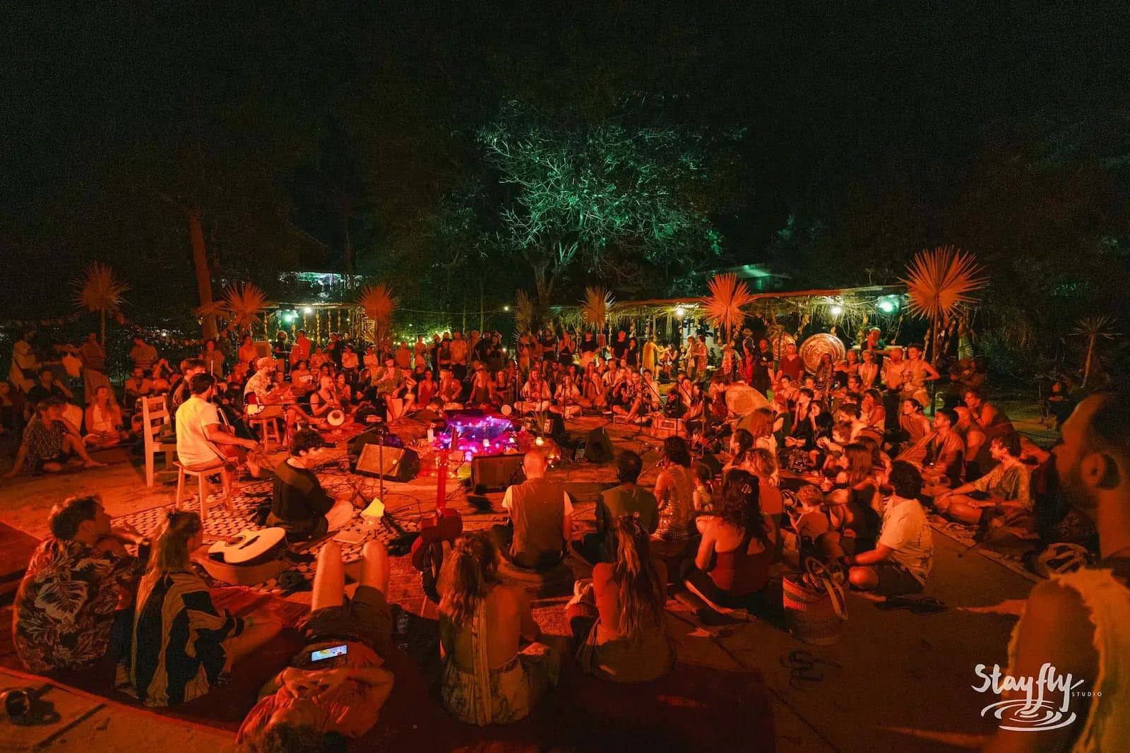 Night gathering seated in circle under trees.