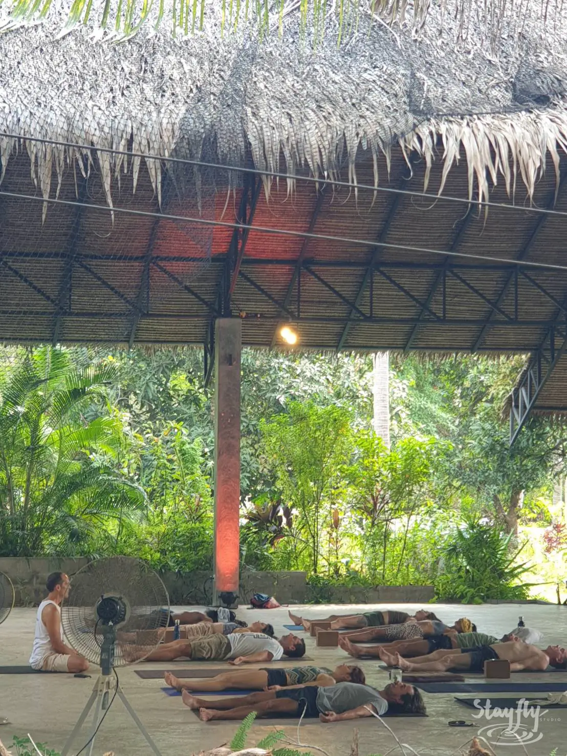 Practitioners lying in savasana in yoga hall.