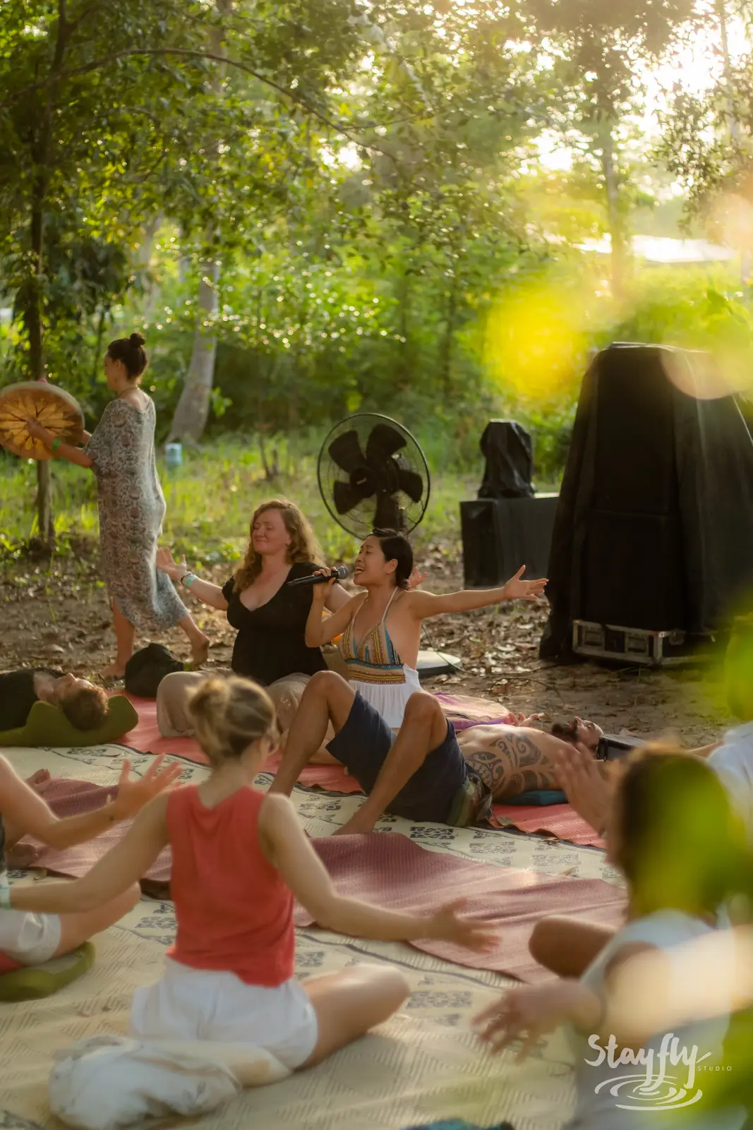 Seated group session on mats under trees at dawn.