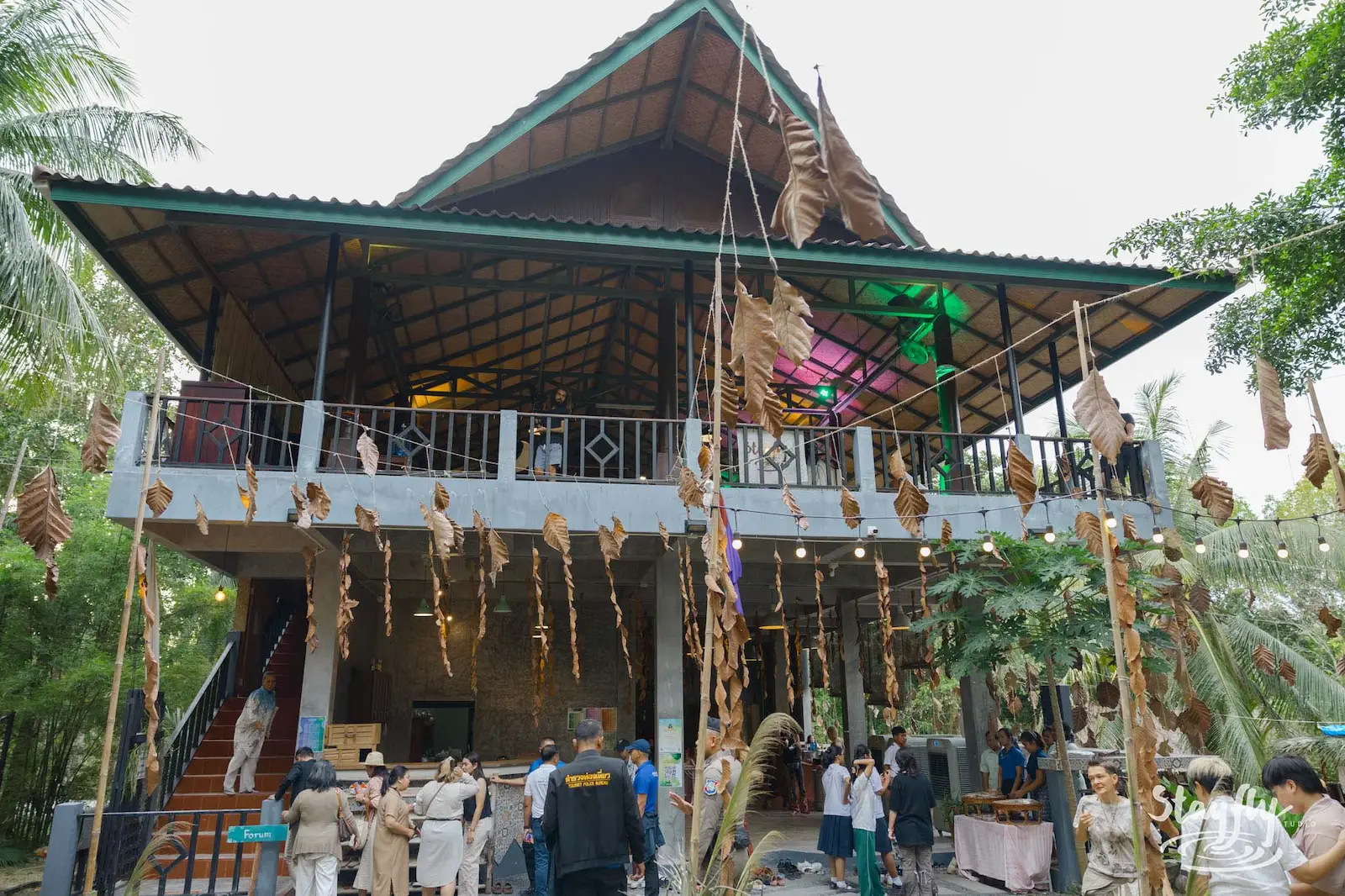 Two-story wooden hall decorated with hanging dried leaves.
