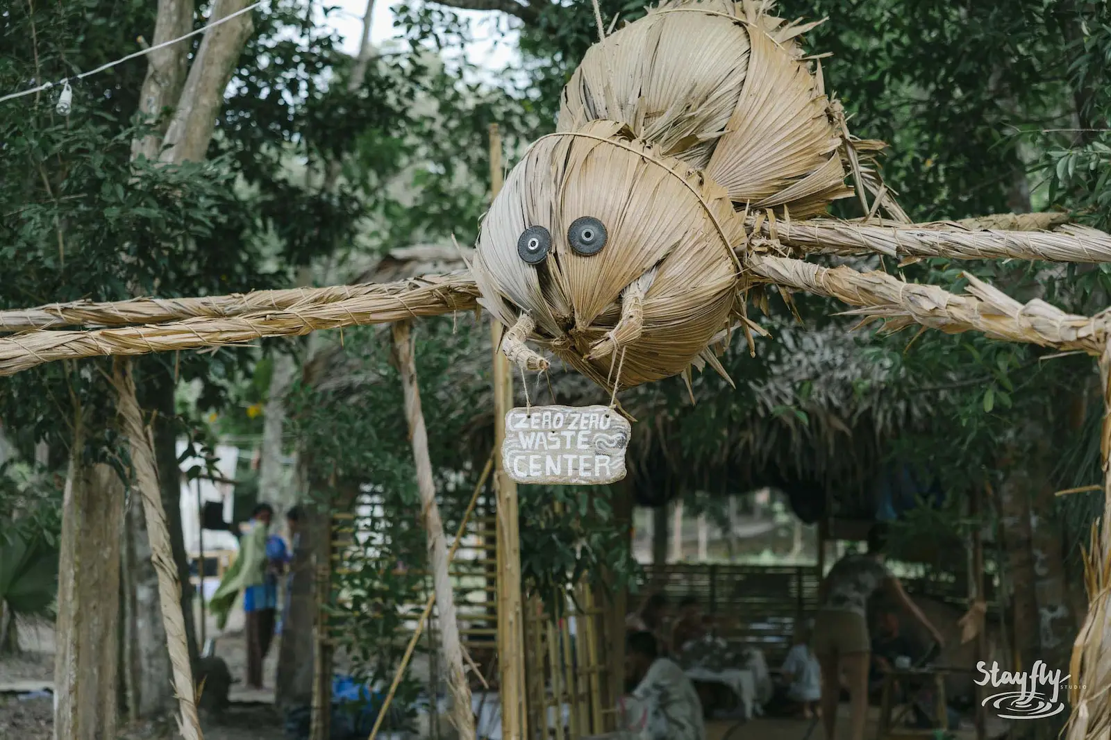 Woven bug sculpture over zero waste sign, daytime.