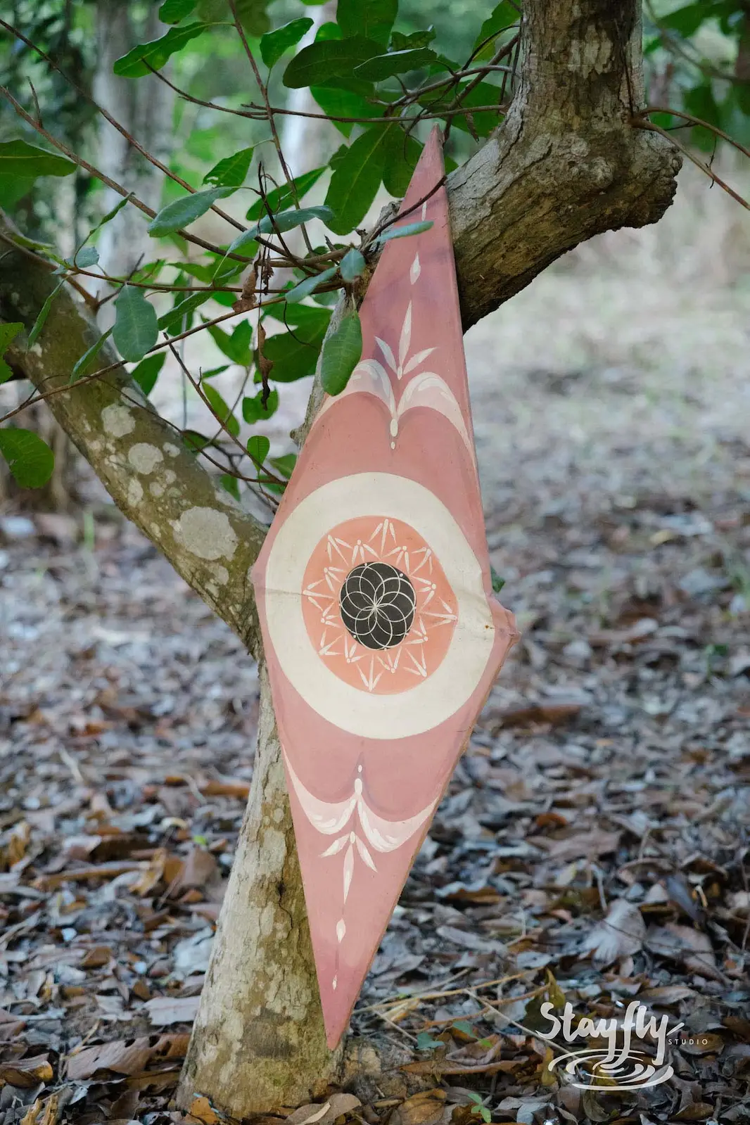 Pink mandala-print fabric hangs from tree branch.