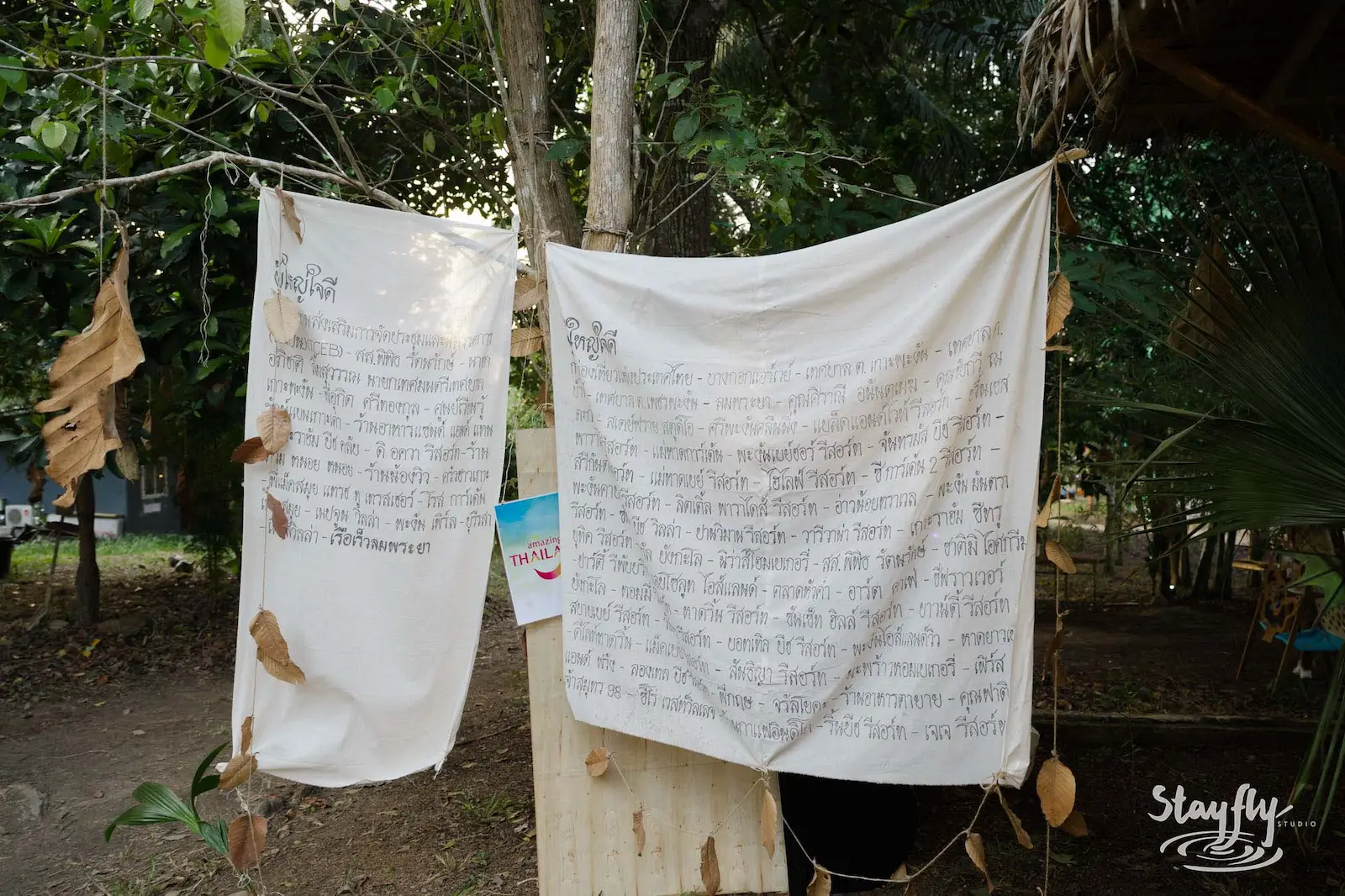 Thai text banners hanging between trees.
