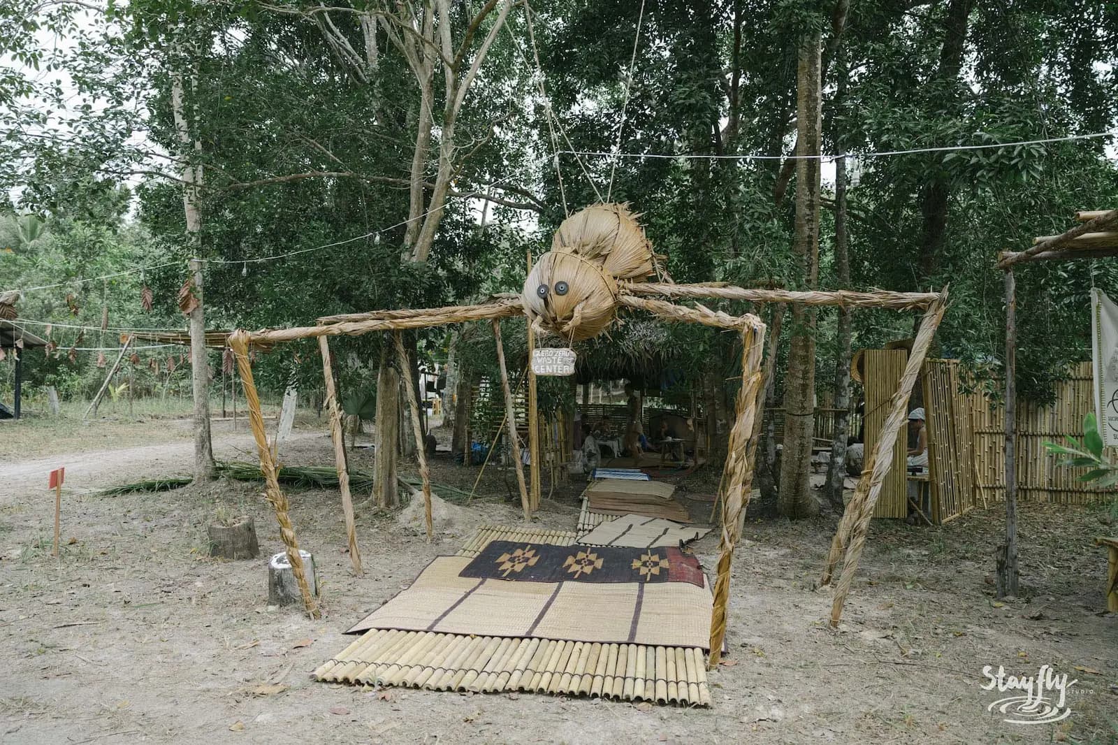 Large wooden insect sculpture structure in forest clearing.
