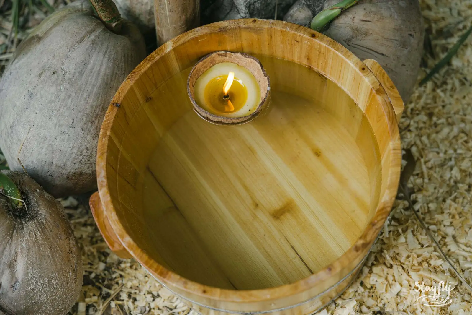 Floating candle in small wooden bucket.