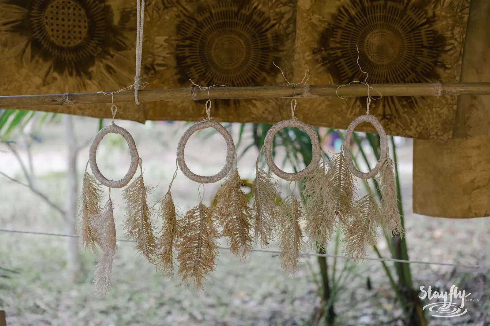 Dreamcatchers with feathers hanging under thatched roof.