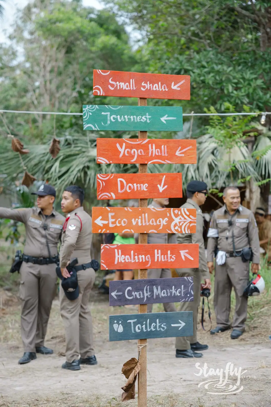 Wooden venue wayfinding signpost with police officers nearby.