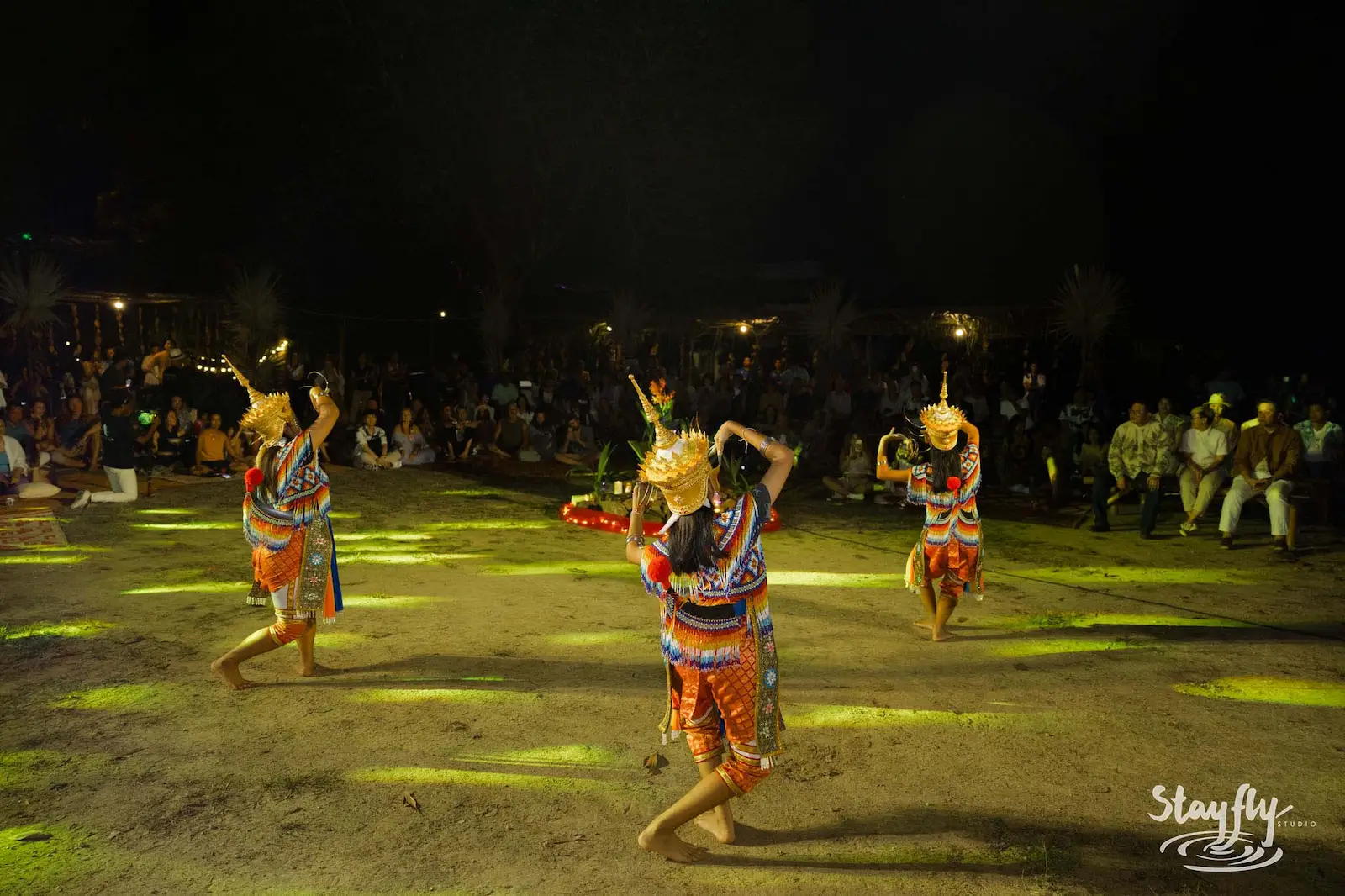 Three masked dancers performing at night.