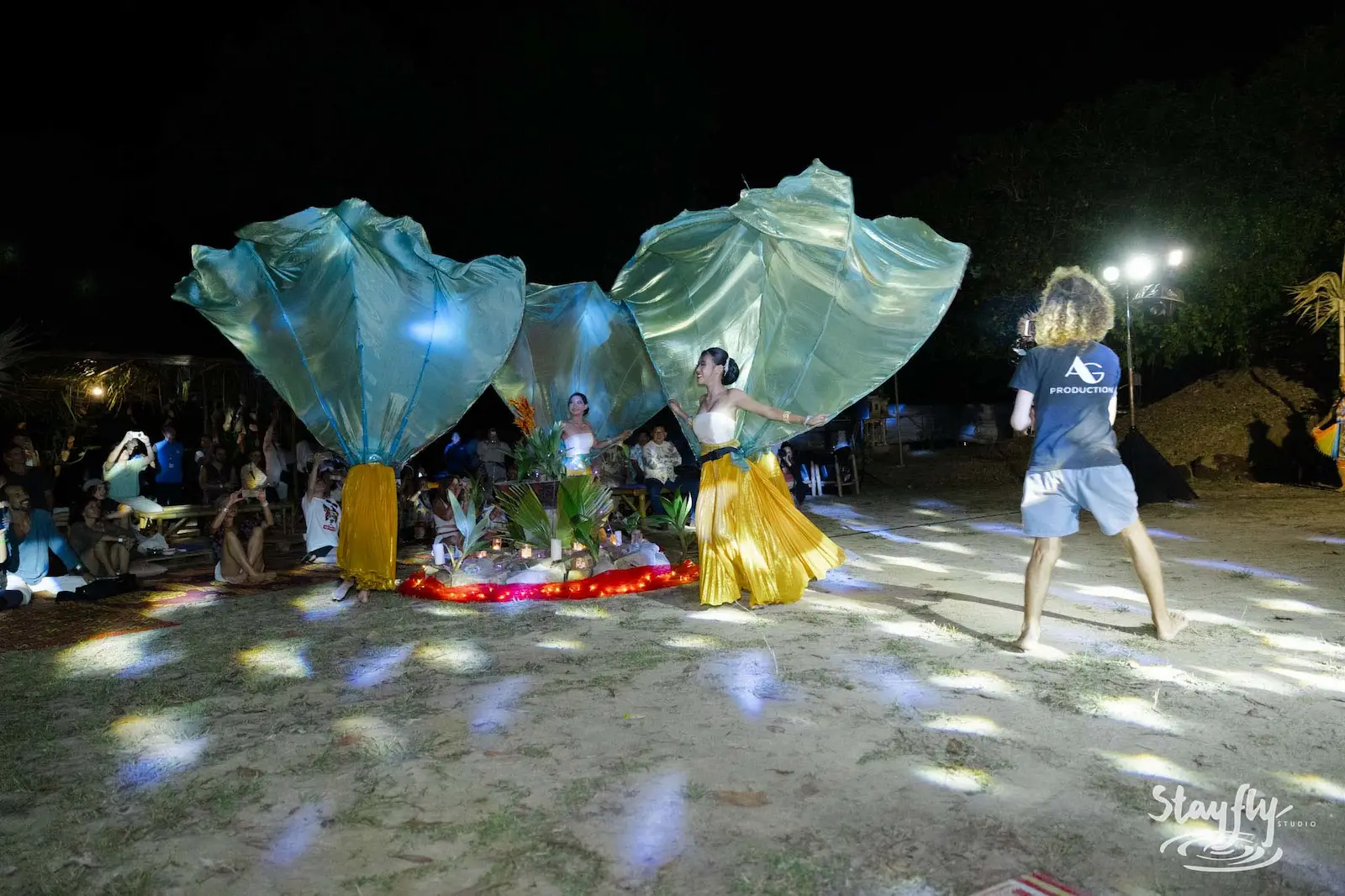 Two dancers with large teal fabric wings performing.