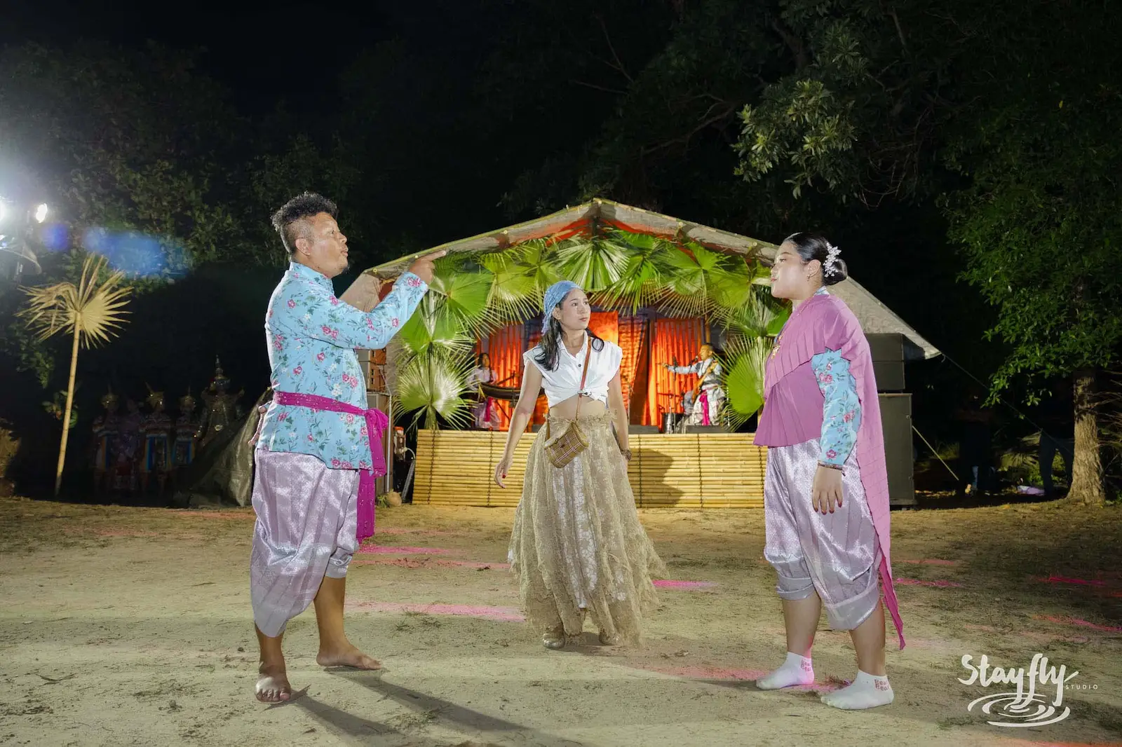 Three dancers in traditional costume performing at night.