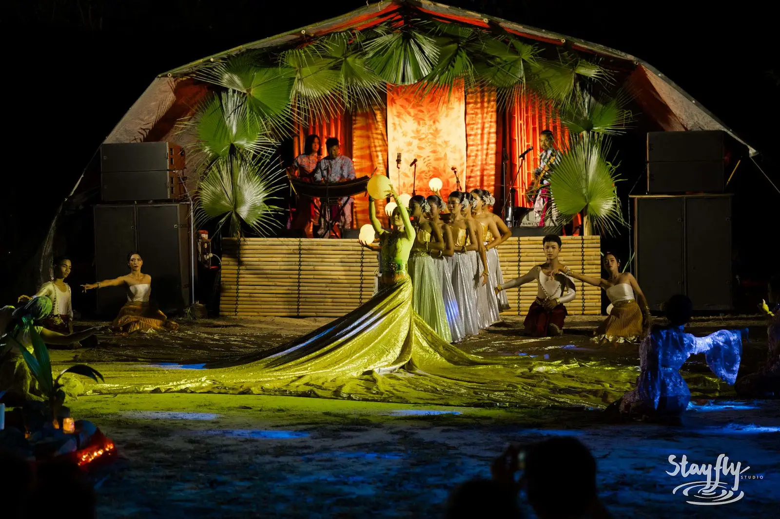 Dancers perform on lit stage with dome-tent backdrop.