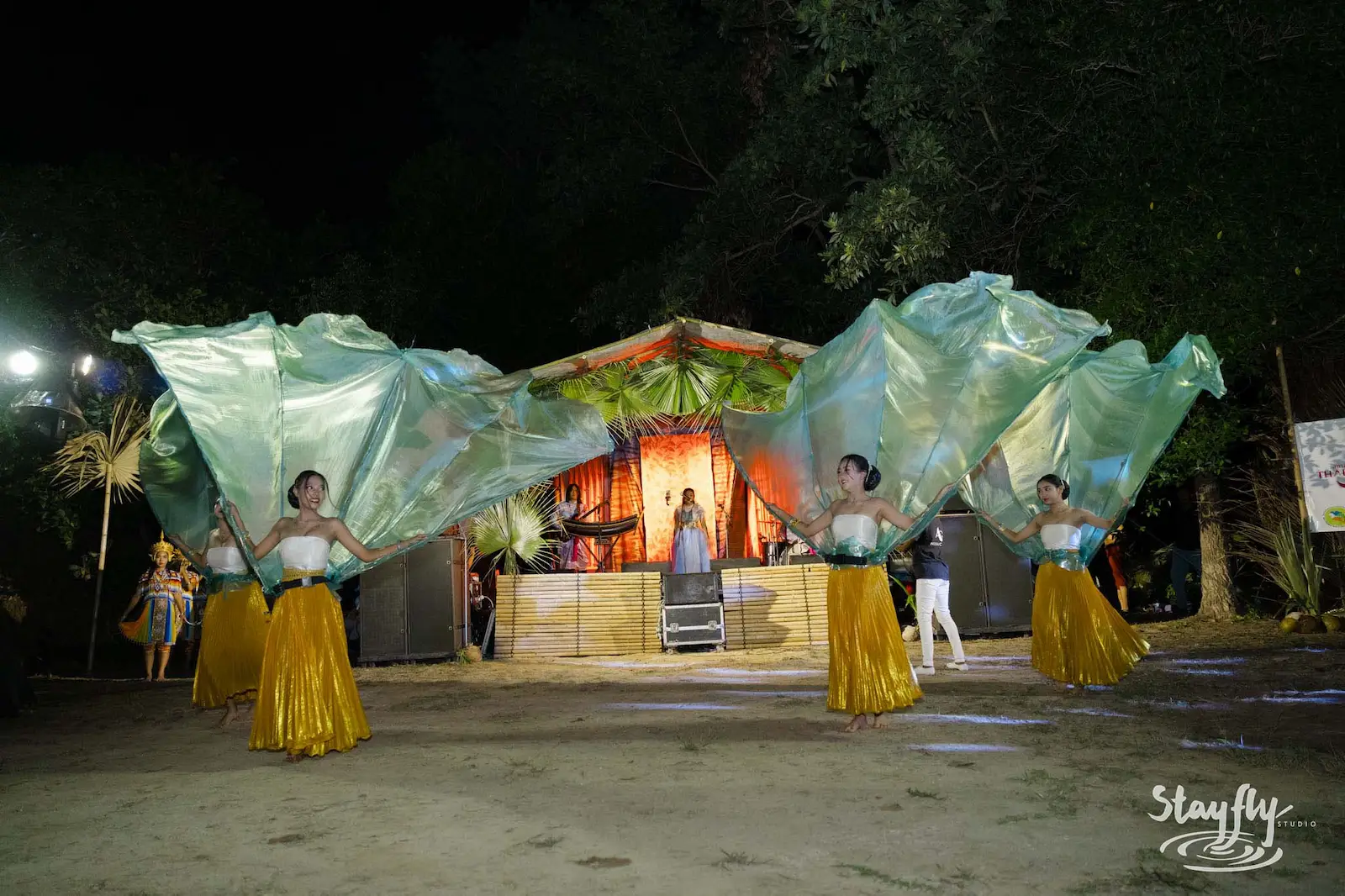 Dancers in green fan costumes before thatch stage.