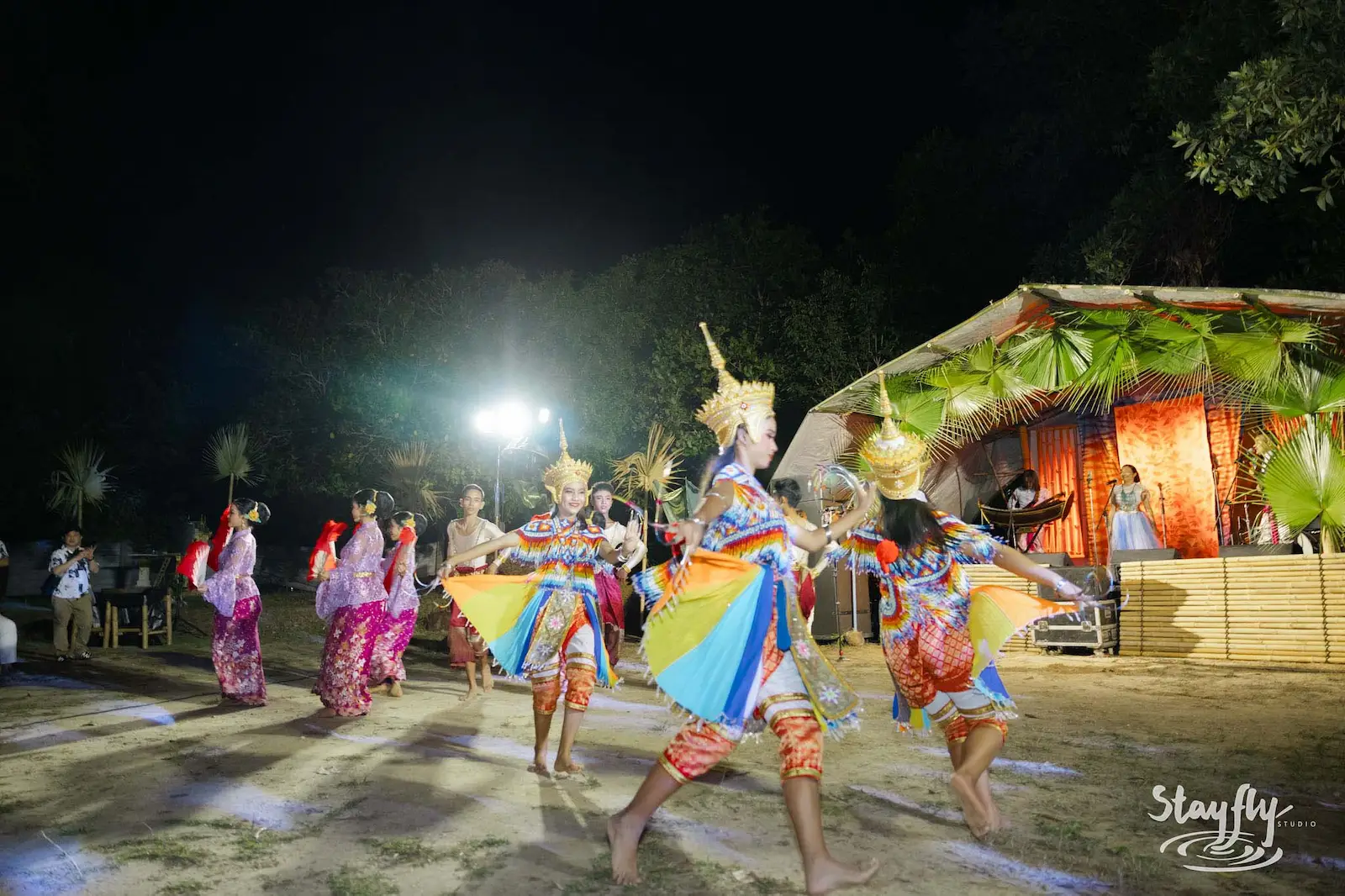Line of costumed dancers parade with fan skirts.