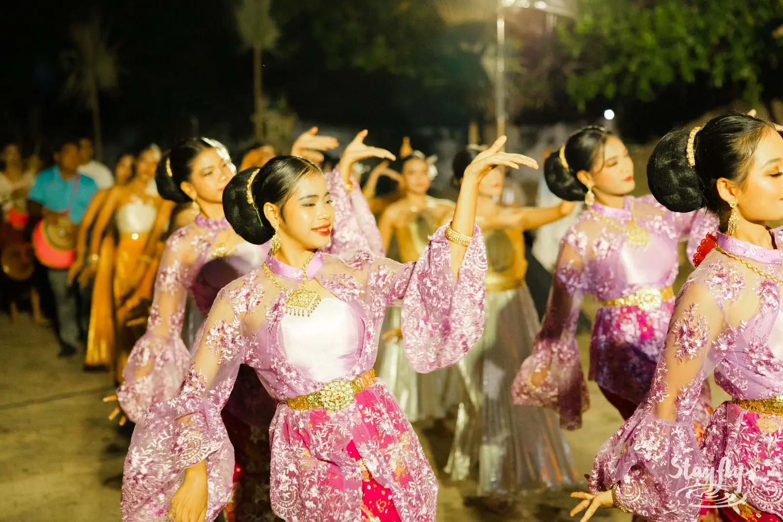 Women in purple lace dress dance in formation.