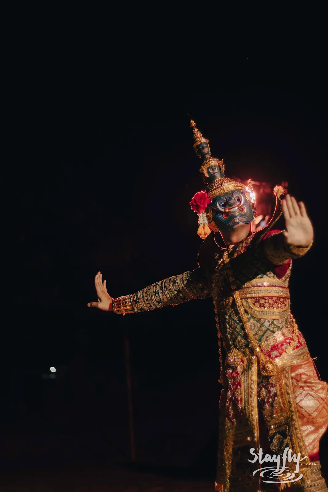 Masked traditional dancer performing at night.