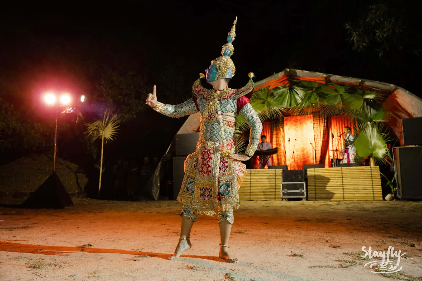 Masked costumed performer posing before night stage.