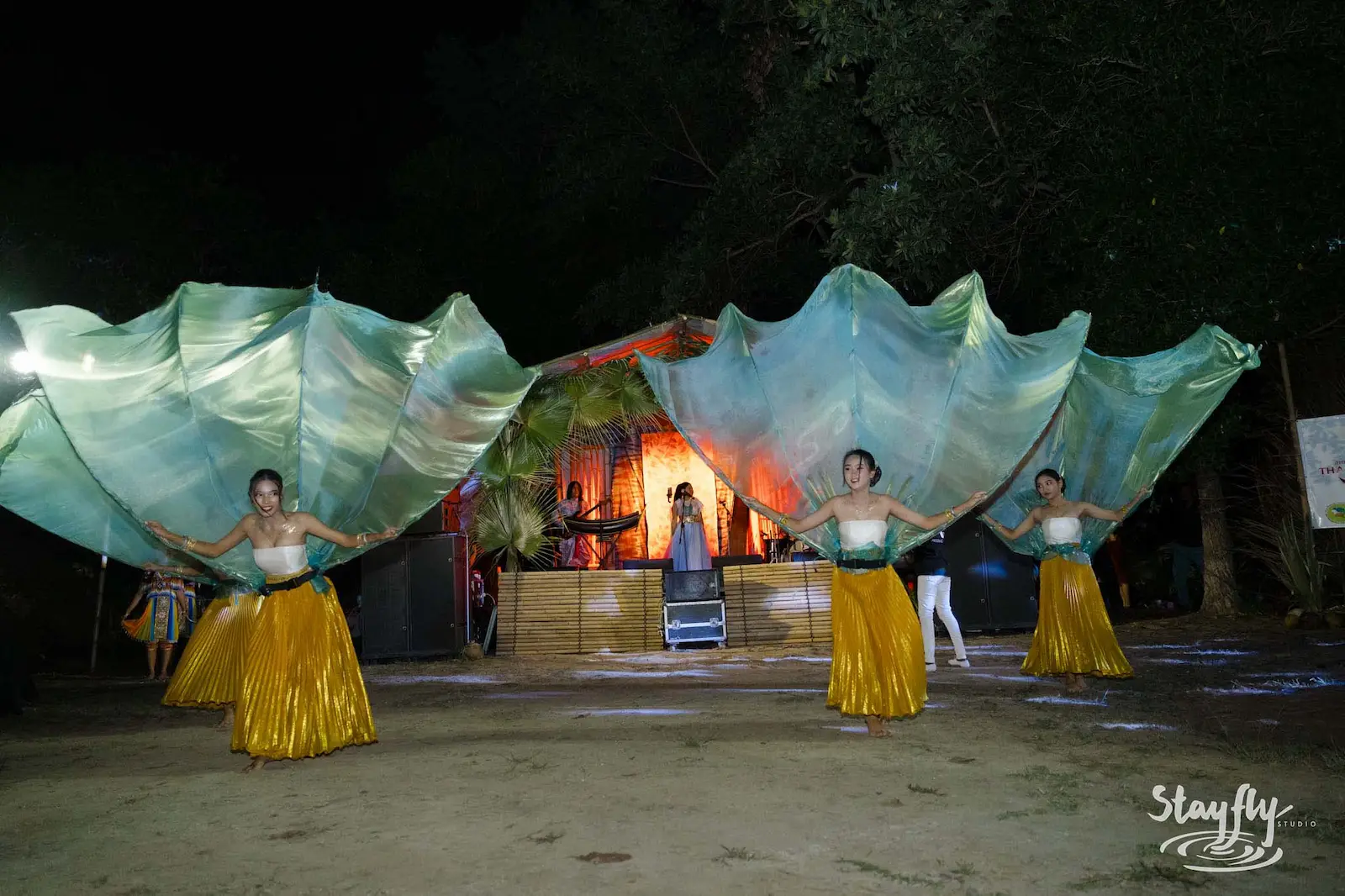 Three dancers with large fan-shaped fabric wings.