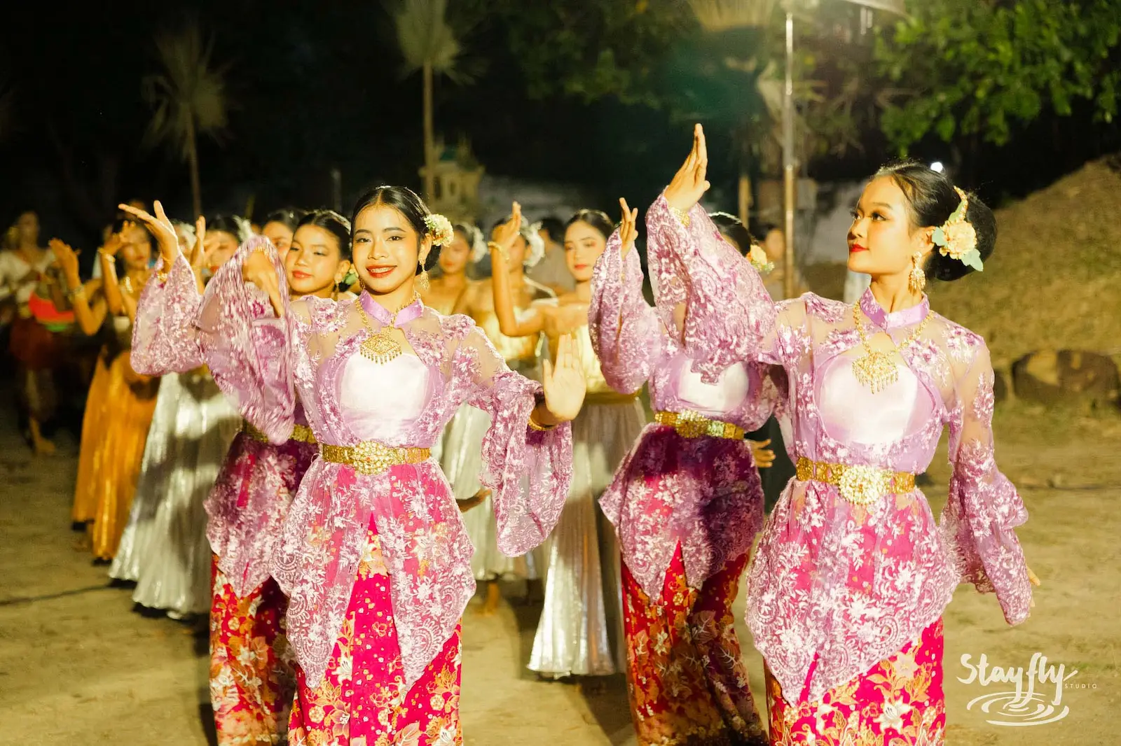 Dancers in pink traditional Thai costume processing at night.