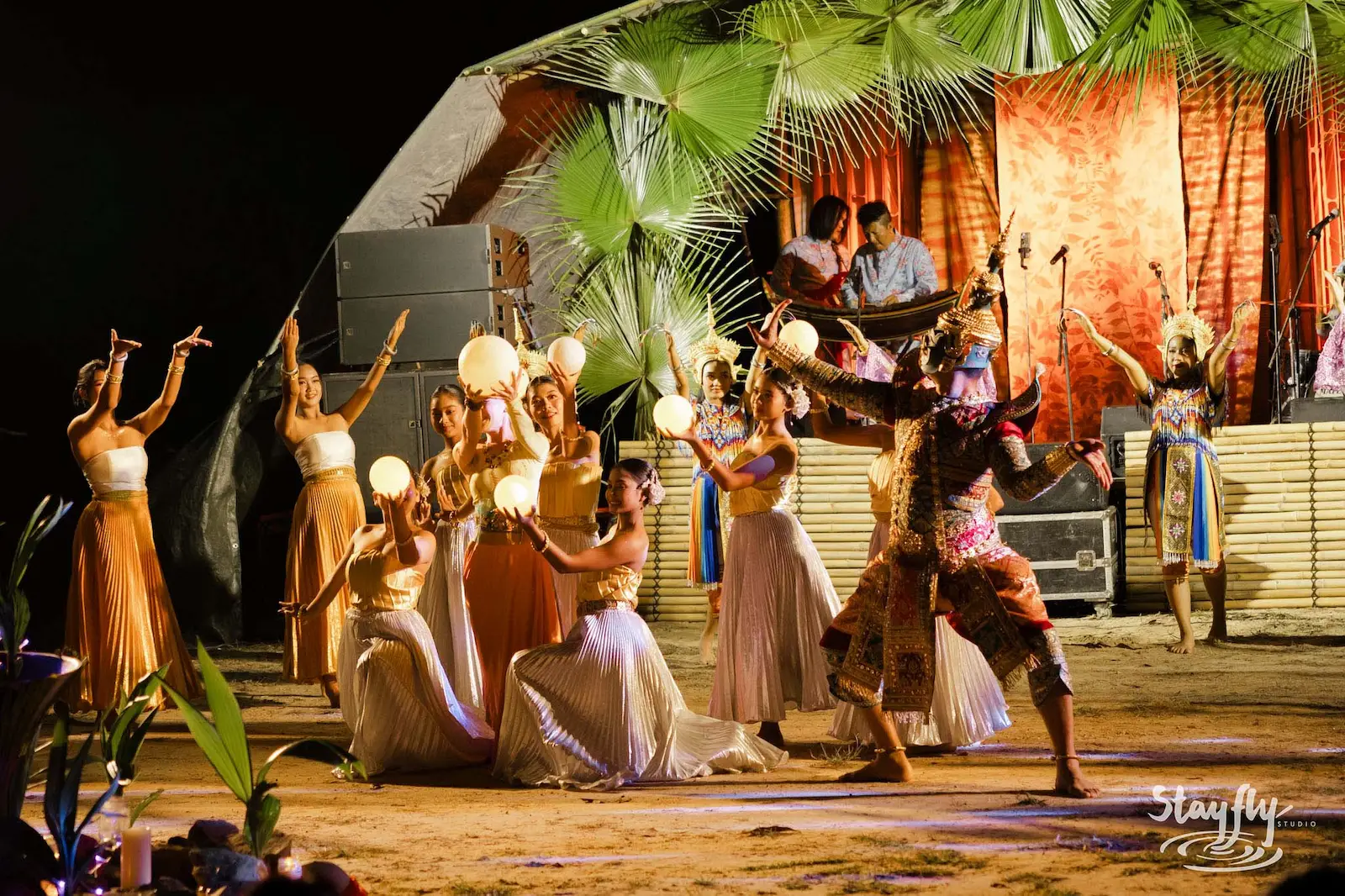 Costumed dance troupe performing on stage at night.