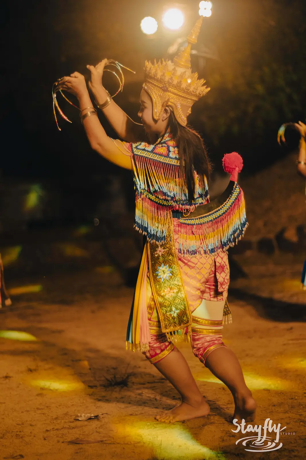 Ornately costumed dancer mid-movement at night.