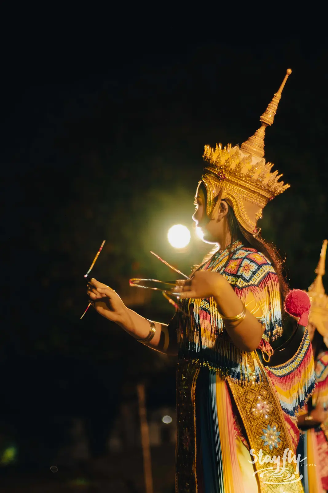 Traditional Thai dancer in gold headdress at night.