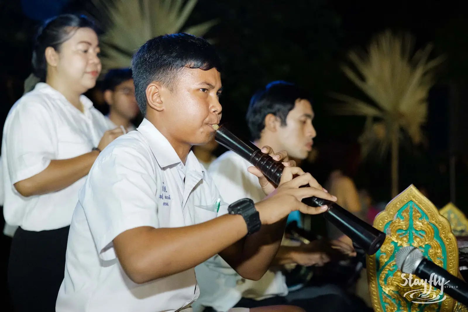 Student musicians playing traditional Thai wind instrument.