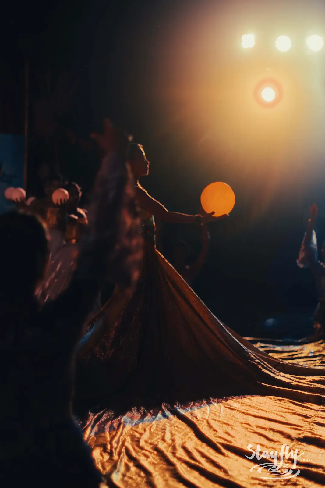 Dancer in flowing gown backlit onstage.