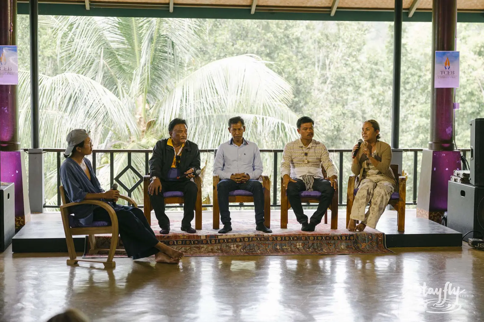 Five panelists seated for discussion in open hall.