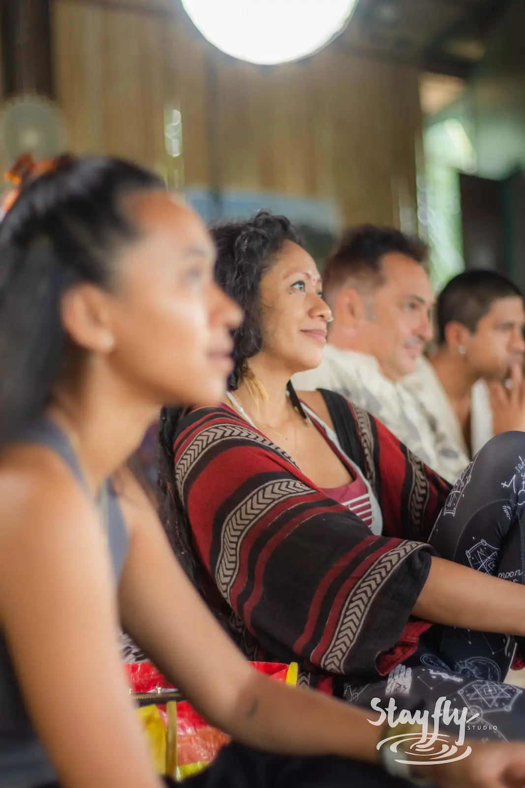 Woman in striped poncho among seated audience.