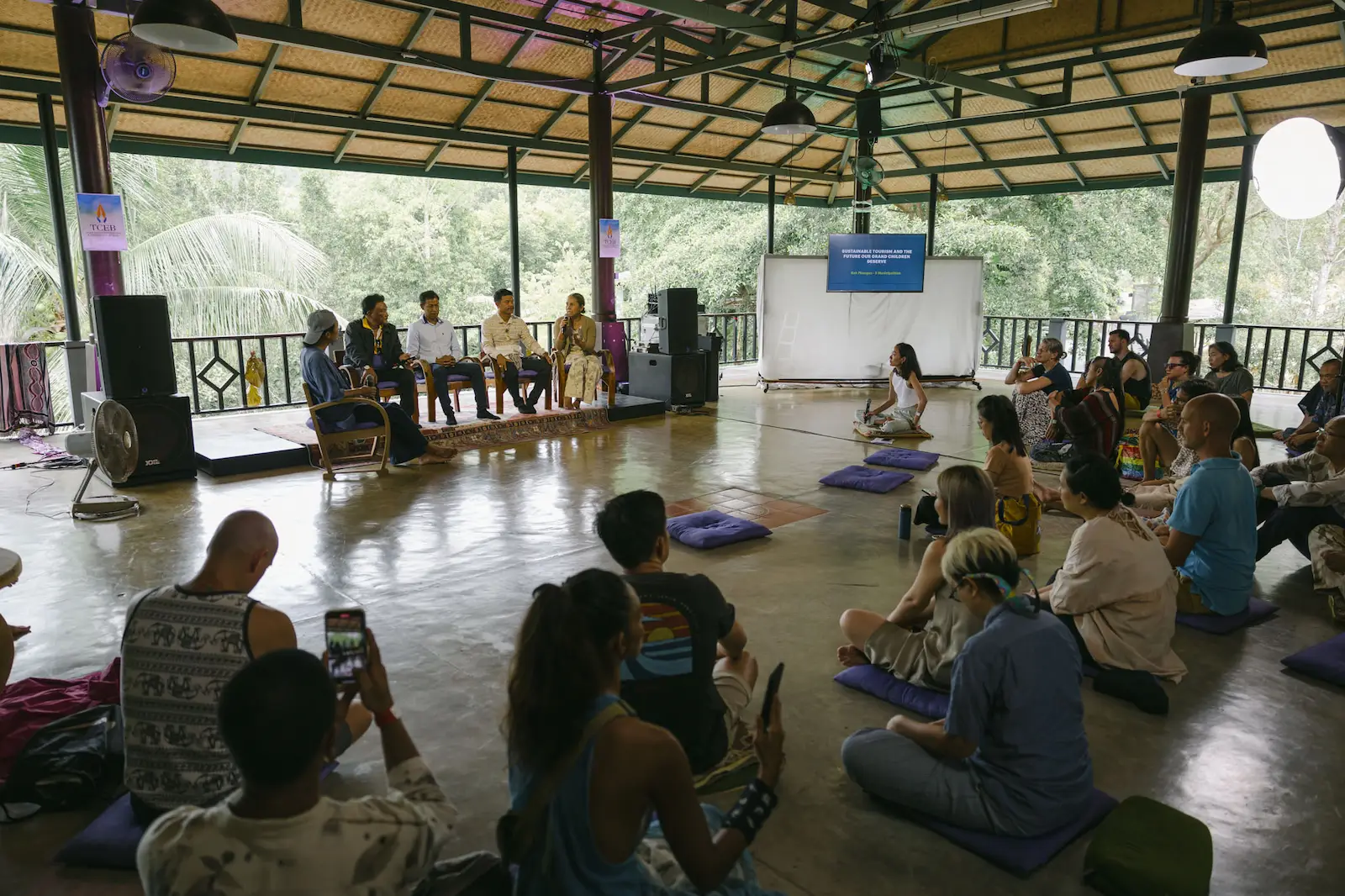 Forum panel discussion beneath open-sided hall.