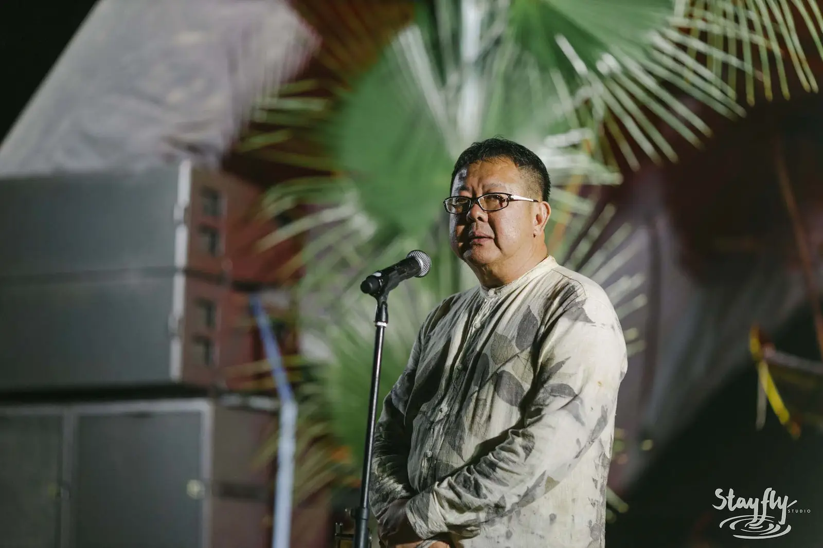 Man speaking at microphone on stage.